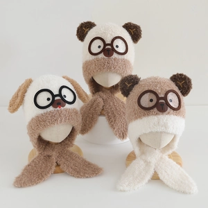 Close-up of plush children's bear hats with built-in scarves and glasses in earthy tones