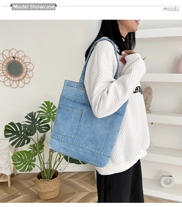 Dettaglio borsa tote in denim azzurro con tasca esterna indossata da una modella donna