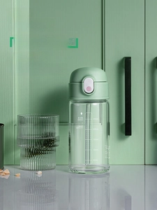 Detail der Glasflasche mit Skalenmarkierungen und minzgrünem Klappdeckel mit Strohhalm