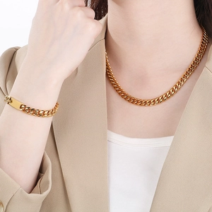 Elegant gold Cuban link chain necklace and bracelet set worn by a fashion model