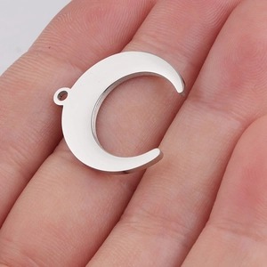 Macro view of a silver moon pendant on a fingertip showing the polished steel finish