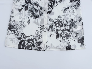 Detail of floral print on lightweight white chiffon fabric with ruffle trim and buttons