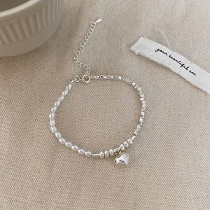 Detailed macro of vintage pearl and silver heart pendant bracelet on linen fabric