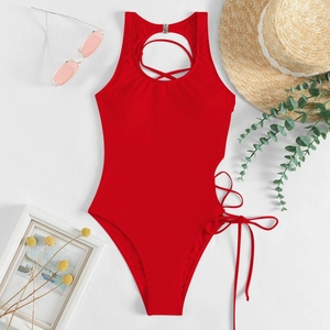 Flat lay of red backless halter swimsuit with side ties and summer accessories