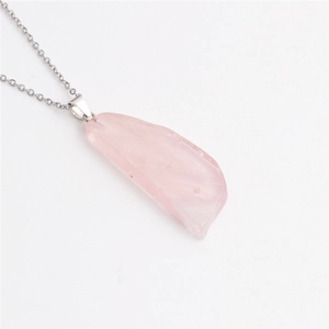 Détail du pendentif en cristal rose irrégulier sur une fine chaîne à maillons argentée