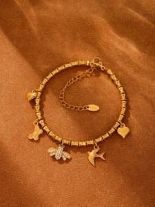 Detailansicht eines goldenen Edelstahl-Bambusarmbands mit Herz- und Bienenanhängern