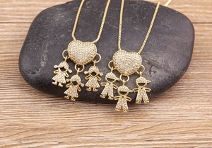 Dettaglio di ciondoli a cuore placcati oro 18k con figure di bambini su sfondo legno