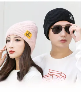Detail shot of knitted beanie hats in pink and black colors with street style letter patches