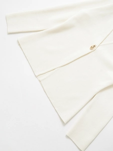Detail view of high-density ivory knit cardigan with decorative gold irregular metal button