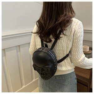 Detailed back view of a black skull-shaped rivet backpack worn by a model