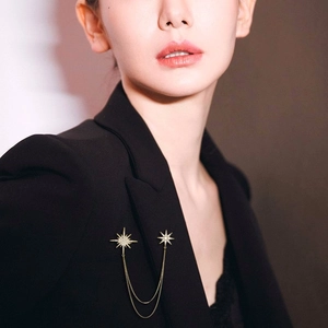 Elegant gold double starburst brooch with chains pinned on a black suit lapel