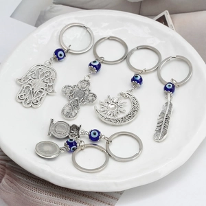 Portachiavi Evil Eye in metallo argentato con mano di Fatima su vassoio di ceramica