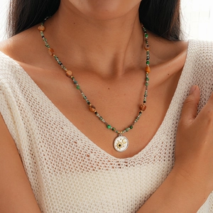 Detailed shot of bohemian beaded necklace with sun and moon celestial metal pendant