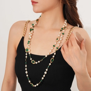 Detail of vintage multilayer pearl necklace with green gemstone and gold chain