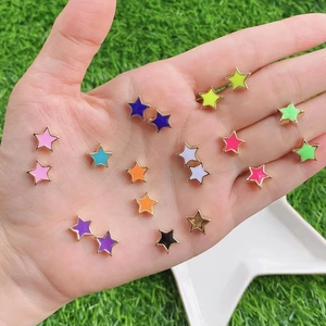 Colorful star shaped stud earrings with oil drip finish held in hand on green lawn