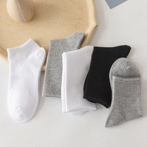 Five pairs of men's cotton crew socks in black white and grey on a wood tray