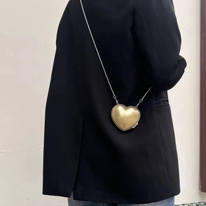 Detailaufnahme einer goldenen herzförmigen Umhängetasche mit glänzendem Finish und Kette.