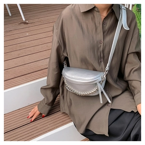 Close-up of a silver saddle bag with chunky metal chain and tassel detail on strap