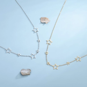 Minimalist gold and silver star pendant necklaces on a fresh blue background
