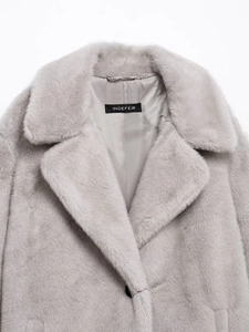 Detail of the oversized lapel and plush faux fur texture on the light grey winter coat