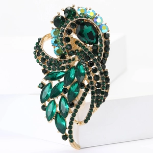 Macro detail of vintage gold brooch with green crystals and iridescent rhinestones