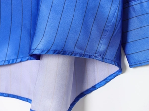 Detailed macro view of curved hem and stitching on blue striped polyester shirt