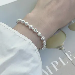 Elegant silver beaded bracelet featuring matte textured and polished spheres on a wrist