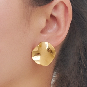 Nahaufnahme von großen unregelmäßigen goldenen Wellenohrringen am Model