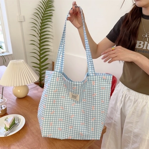 Detail view of blue and white checkered canvas tote bag with pink bow print