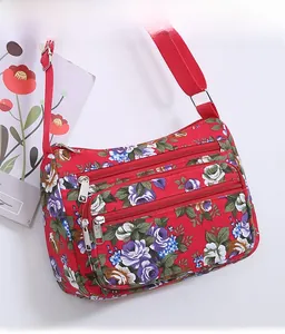 Close-up of red floral crossbody bag with three zipper pockets and adjustable strap