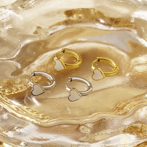 Boucles d'oreilles chic en forme de cœur émaillé or et argent sur un plateau de luxe