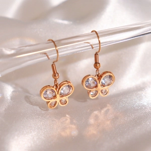 Elegant rose gold butterfly drop earrings with zircon crystals on white silk background