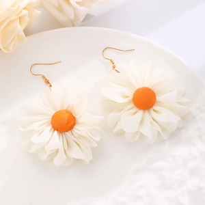 Detail view of woven raffia daisy earrings with orange fabric center and gold hooks