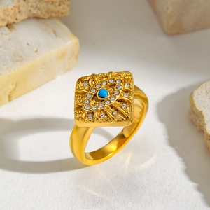 Macro detail of gold signet ring with hammer texture and blue crystal evil eye