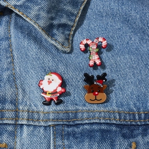 Nahaufnahme von Weihnachtsmann-, Rentier- und Zuckerstangen-Broschen auf Denim-Jacke