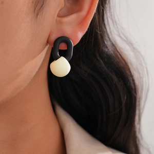Close-up of a minimalist black U-shaped ring earring with a cream spherical accent