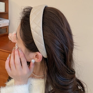 Close-up of beige quilted leather headband showing elegant texture and wide design
