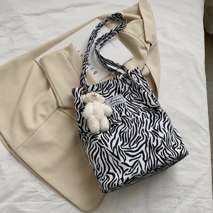 Detail of zebra pattern canvas tote bag with a cute white plush bear keychain accessory