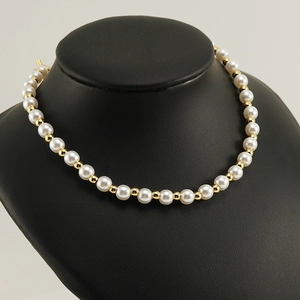 Close-up of elegant pearl and 18k gold bead chain necklace on a black mannequin bust