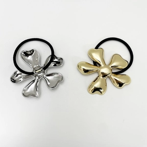Close-up of gold and silver metallic five-petal flower hair ties on white background