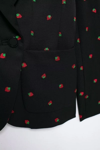 Détail du blazer noir avec broderies de fraises montrant le tissu et la poche