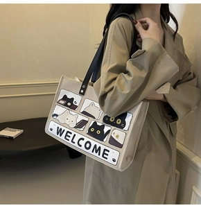Detail of canvas tote bag with cartoon cat print and black leather straps with rivets