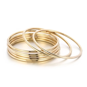 Stack of minimalist 18k gold plated titanium steel bangles on white background
