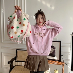 Close-up of fluffy off-white tote bag with multi-colored polka dots and pink strap