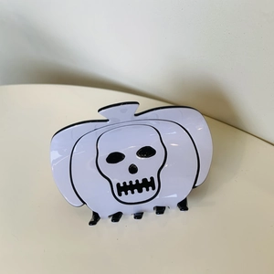 Detail of white Halloween hair claw clip featuring a skull pumpkin design with black teeth