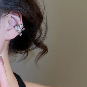 Detailed view of silver cuff earring with zircon inlays on a woman's ear cartilage