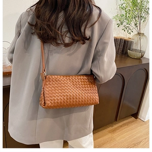 Gros plan du sac à bandoulière tressé marron avec texture Intrecciato et sangle réglable