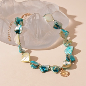 Dettaglio della collana stile marino con conchiglie verde acqua e pendente oro