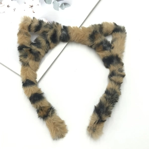 Detail of leopard print plush cat ear headband with soft faux fur texture on white background