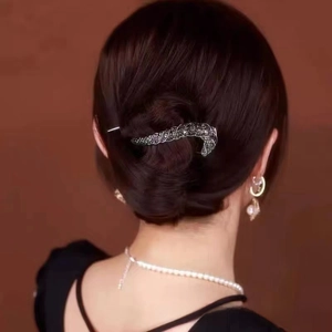 Close-up of elegant twisted hair clip with sparkling dark crystals on a classic hair bun